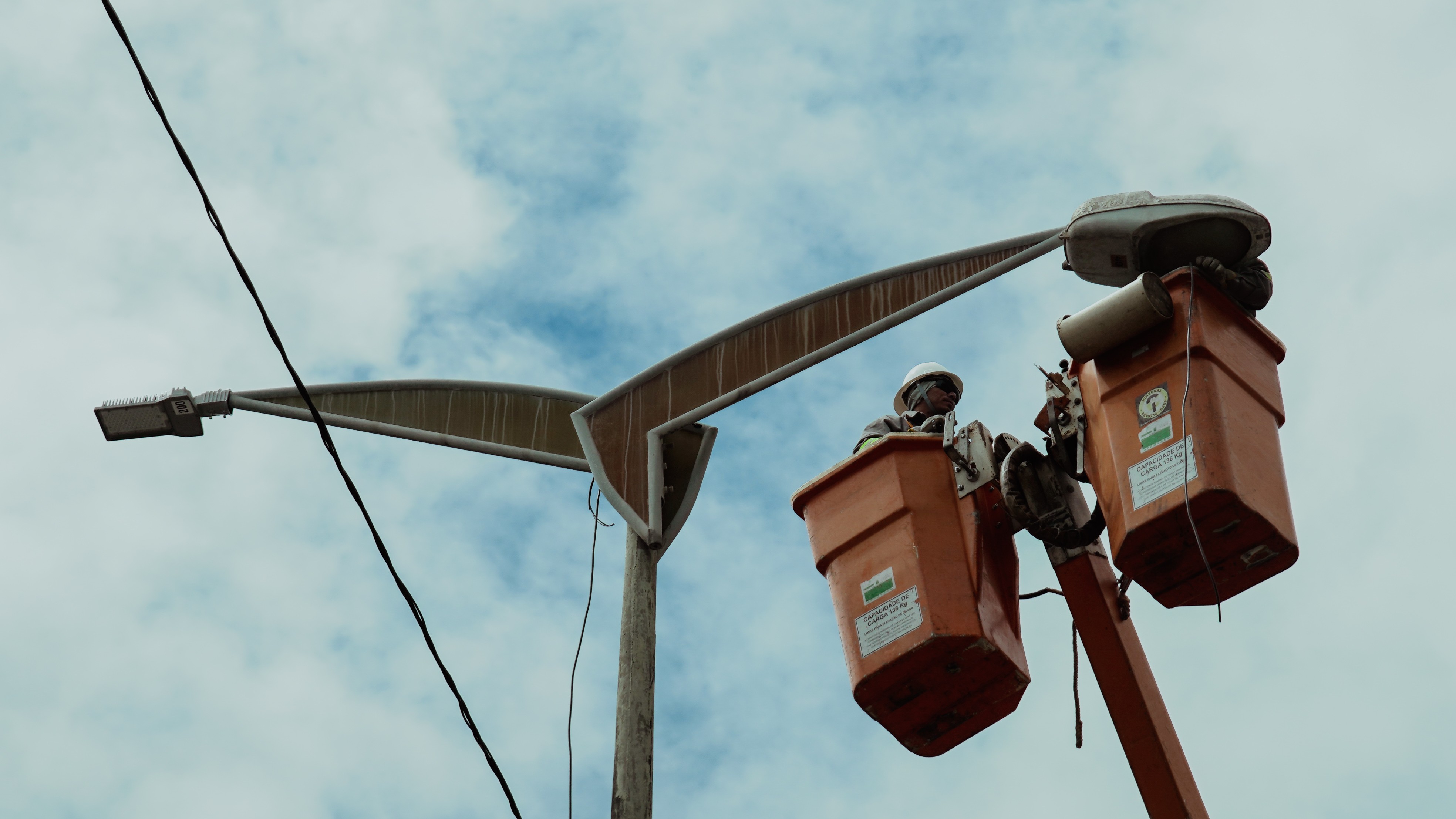 operários em uma plataforma instalar lâmpada em poste de iluminação